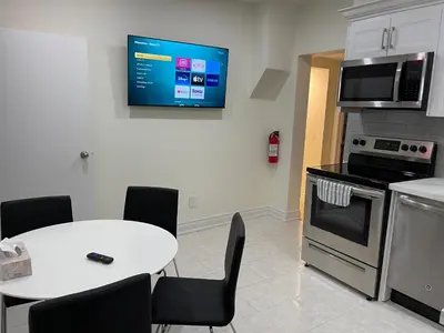 a kitchen with a table and a tv on the wall at Two-bedroom Suite with King Bed-4 Minutes to The Falls in Niagara Falls