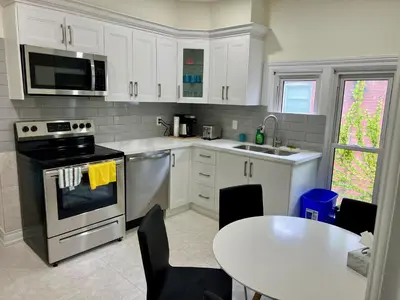 a kitchen with white cabinets and a table and a stove at Two-bedroom Suite with King Bed-4 Minutes to The Falls in Niagara Falls