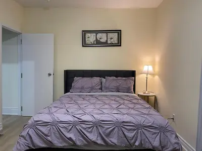 a bedroom with a large bed with a purple comforter at Two-bedroom Suite with King Bed-4 Minutes to The Falls in Niagara Falls
