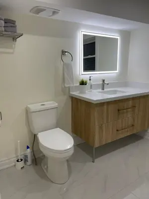 a bathroom with a toilet and a sink and a window at Two-bedroom Suite with King Bed-4 Minutes to The Falls in Niagara Falls