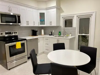 a white kitchen with a white table and chairs at Two-bedroom Suite with King Bed-4 Minutes to The Falls in Niagara Falls