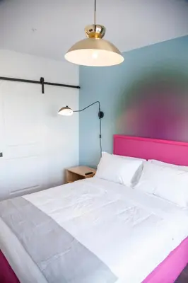 a bedroom with a white bed with a pink headboard at The Laundry Rooms Gaslight Cambridge in Cambridge