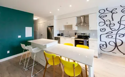 a kitchen with a white counter and yellow chairs at The Laundry Rooms Gaslight Cambridge in Cambridge