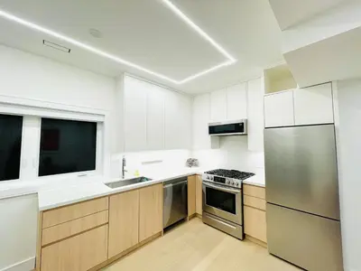 a kitchen with white cabinets and a stainless steel refrigerator at Urban 2-bed apartment in the Beaches in Toronto