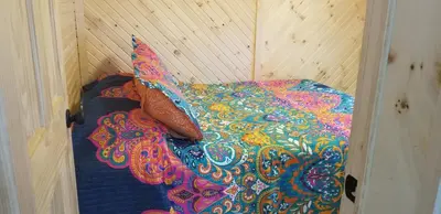 a bed with a colorful comforter and two pillows at Stoneburg Cove Cottages in Carrying Place