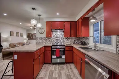 a kitchen with red cabinets and a stove top oven at Rustic Elegant Stays in Niagara Benchlands in Beamsville