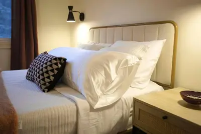 a bed with white sheets and pillows on it at Rustic Elegant Stays in Niagara Benchlands in Beamsville