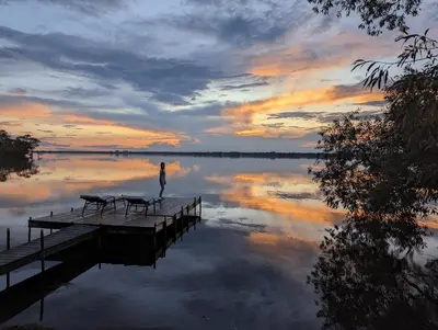 a person standing on a dock on a lake at sunset at Waterfront Boutique Accommodation in PEC - Suite 3 in Belleville