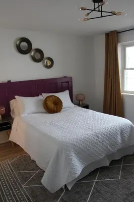 a bedroom with a white bed with a wooden headboard at 4 Guest Suite with Waterfront Views at Fancie's PEC - Suite 2 in Belleville