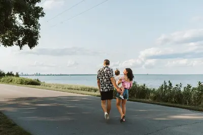 a man and a woman walking down a road with a baby at Luxurious Lakeview Oasis in the Heart of Hamilton With Large Backyard in Hamilton