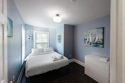 a bedroom with a bed with blue walls and a window at Luxurious Lakeview Oasis in the Heart of Hamilton With Large Backyard in Hamilton
