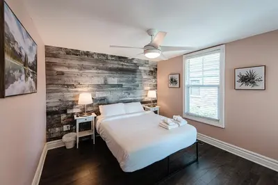 a bedroom with a white bed and a wooden wall at Luxurious Lakeview Oasis in the Heart of Hamilton With Large Backyard in Hamilton