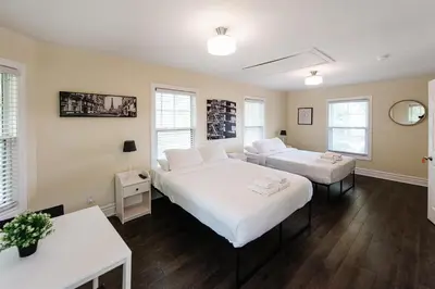 two beds in a room with two tables and windows at Luxurious Lakeview Oasis in the Heart of Hamilton With Large Backyard in Hamilton