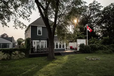 a house with a flag in the yard at Hamilton's Beach House Stunning Lake Views! Modern Open concept HotTub,firepit, 3BR in Hamilton