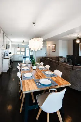 a dining room with a long table and white chairs at Hamilton's Beach House Stunning Lake Views! Modern Open concept HotTub,firepit, 3BR in Hamilton