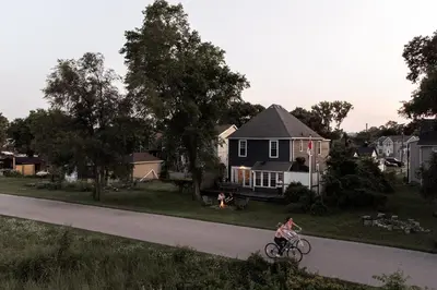 a woman riding a bike down a road in front of a house at Hamilton's Beach House Stunning Lake Views! Modern Open concept HotTub,firepit, 3BR in Hamilton