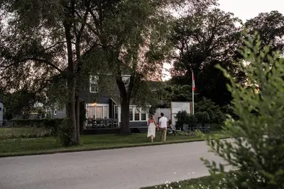 two people walking down a street in front of a house at Hamilton's Beach House Stunning Lake Views! Modern Open concept HotTub,firepit, 3BR in Hamilton