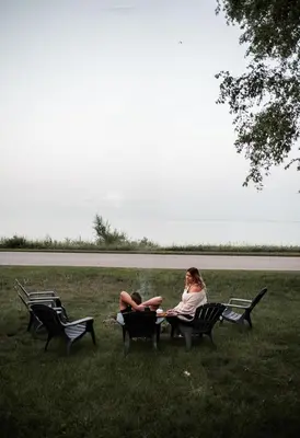 two people sitting on benches in the grass at Hamilton's Beach House Stunning Lake Views! Modern Open concept HotTub,firepit, 3BR in Hamilton