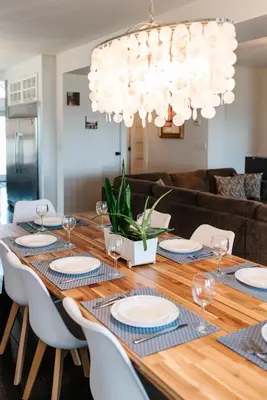 a dining room table with chairs and a chandelier at Hamilton's Beach House Stunning Lake Views! Modern Open concept HotTub,firepit, 3BR in Hamilton