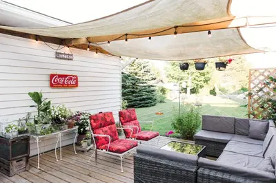 a patio with a couch and chairs and a cocacola sign at The Old Homestead - Gorgeous backyard right in The Heart of Picton in Picton