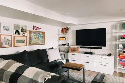 a living room with a black couch and a flat screen tv at The Old Homestead - Gorgeous backyard right in The Heart of Picton in Picton