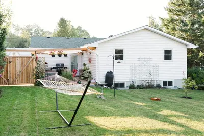 a yard with a hammock in front of a house at The Old Homestead - Gorgeous backyard right in The Heart of Picton in Picton