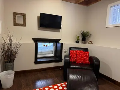 a living room with a black chair with a red pillow at The Farm Shed Guelph Elora in Guelph