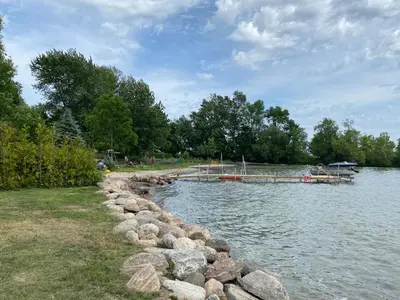 a river with a dock and rocks in the water at Swing Bridge Cottage on Lake Simcoe - Waterfront in Brechin