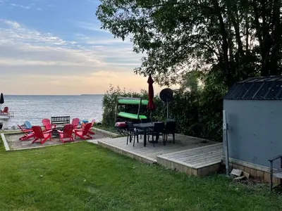 a group of chairs and tables on a deck near the water at Swing Bridge Cottage on Lake Simcoe - Waterfront in Brechin