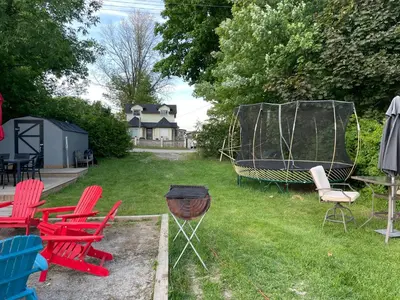 a group of chairs and a grill in a yard at Swing Bridge Cottage on Lake Simcoe - Waterfront in Brechin