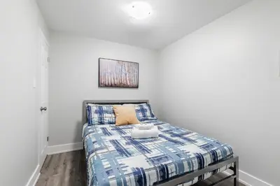a bedroom with a bed with a blue and white comforter at 1BR Basement Condo - James Street in Hamilton