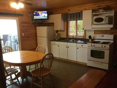 a kitchen with a table and a stove and microwave at Sandy Shore Cottages Luxury Resort on Rice Lake in Harwood