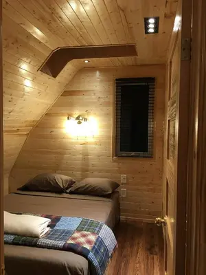a bedroom with a bed in a wooden cabin at Sandy Shore Cottages Luxury Resort on Rice Lake in Harwood