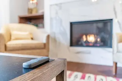 a remote control on a table in a living room with a fireplace at Luxurious and Spacious 4BR Home Near Downtown in Burlington