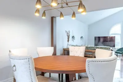 a dining room with a wooden table and white chairs at Luxurious and Spacious 4BR Home Near Downtown in Burlington