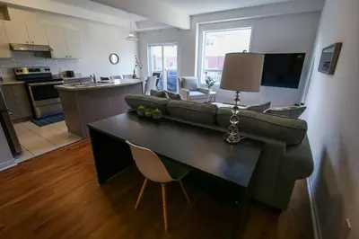 a living room and kitchen with a couch and a table at Townhome Steps From Lake Ontario in Hamilton