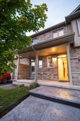a house with a front porch with a car parked in front at Modern & Cozy Retreat Lake Ontario & Wine Country in Grimsby
