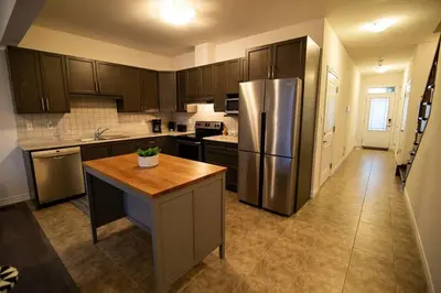 a kitchen with a stainless steel refrigerator and a table at Modern & Cozy Retreat Lake Ontario & Wine Country in Grimsby