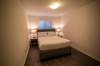 a bedroom with a bed with two lamps on it at Modern & Cozy Retreat Lake Ontario & Wine Country in Grimsby