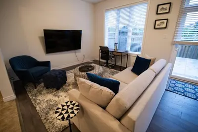 a living room with a couch and a flat screen tv at Modern & Cozy Retreat Lake Ontario & Wine Country in Grimsby