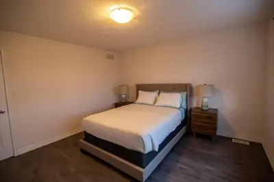 a bedroom with a bed and a night stand with a lamp at Modern & Cozy Retreat Lake Ontario & Wine Country in Grimsby