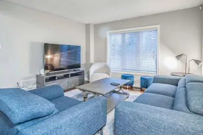 a living room with blue couches and a tv at Stylish 4BR Home 20 Mins from YYZ in Mississauga