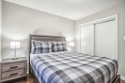 a bedroom with a bed and a night stand with a lamp at Stylish 4BR Home 20 Mins from YYZ in Mississauga