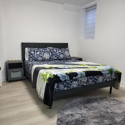 a bedroom with a bed with blue and white sheets and a window at Bright 2 Bedroom Basement Apartment in Angus in Angus