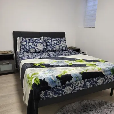 a bedroom with a bed with a blue and white comforter at Bright 2 Bedroom Basement Apartment in Angus in Angus