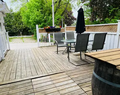 a wooden deck with a table and chairs and an umbrella at Barker House 3# Suite-heart of oldtown in Niagara on the Lake