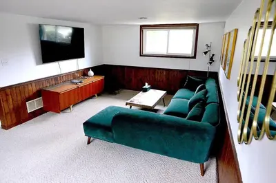 a living room with a green couch and a tv at Cellar House NOTL - Entire Home in the Heart of Niagara-on-the-Lake in Niagara on the Lake