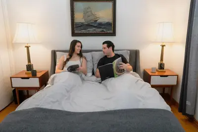 a man and a woman sitting in bed with a book at Cellar House NOTL - Entire Home in the Heart of Niagara-on-the-Lake in Niagara on the Lake