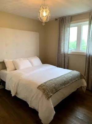 a bedroom with a large white bed with a chandelier at 4 Bedrms, Indoor HotTub, Wineries & Niagara Falls in Beamsville