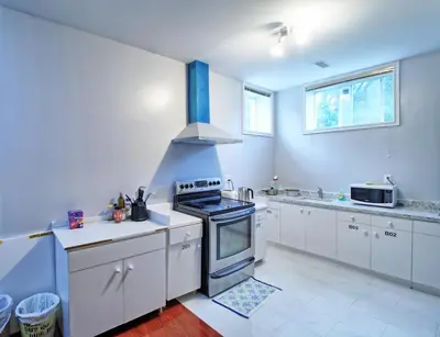 a large kitchen with white cabinets and a stove at Bright Basement & Private Bathroom, free Parking in Vaughan